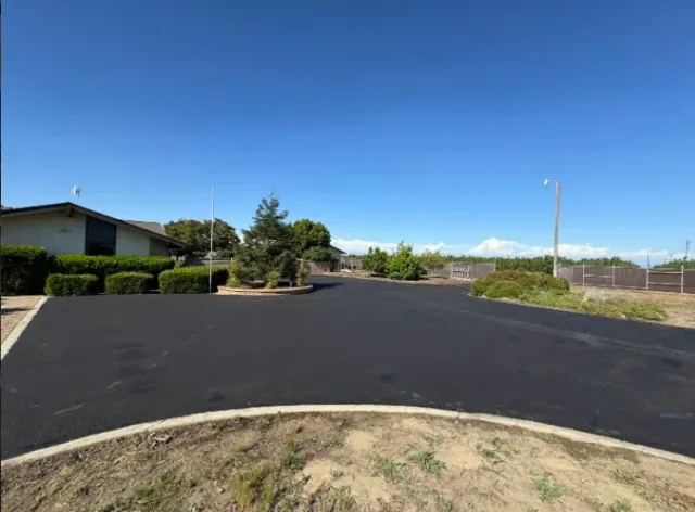 Empty paved parking lot beside a building under a clear blue sky