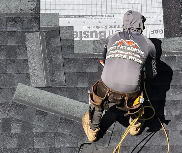 Roofer climbing a ladder with a bundle of shingles
