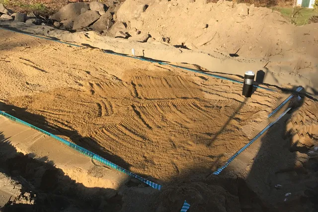 A dirt field with sand and blue lines
