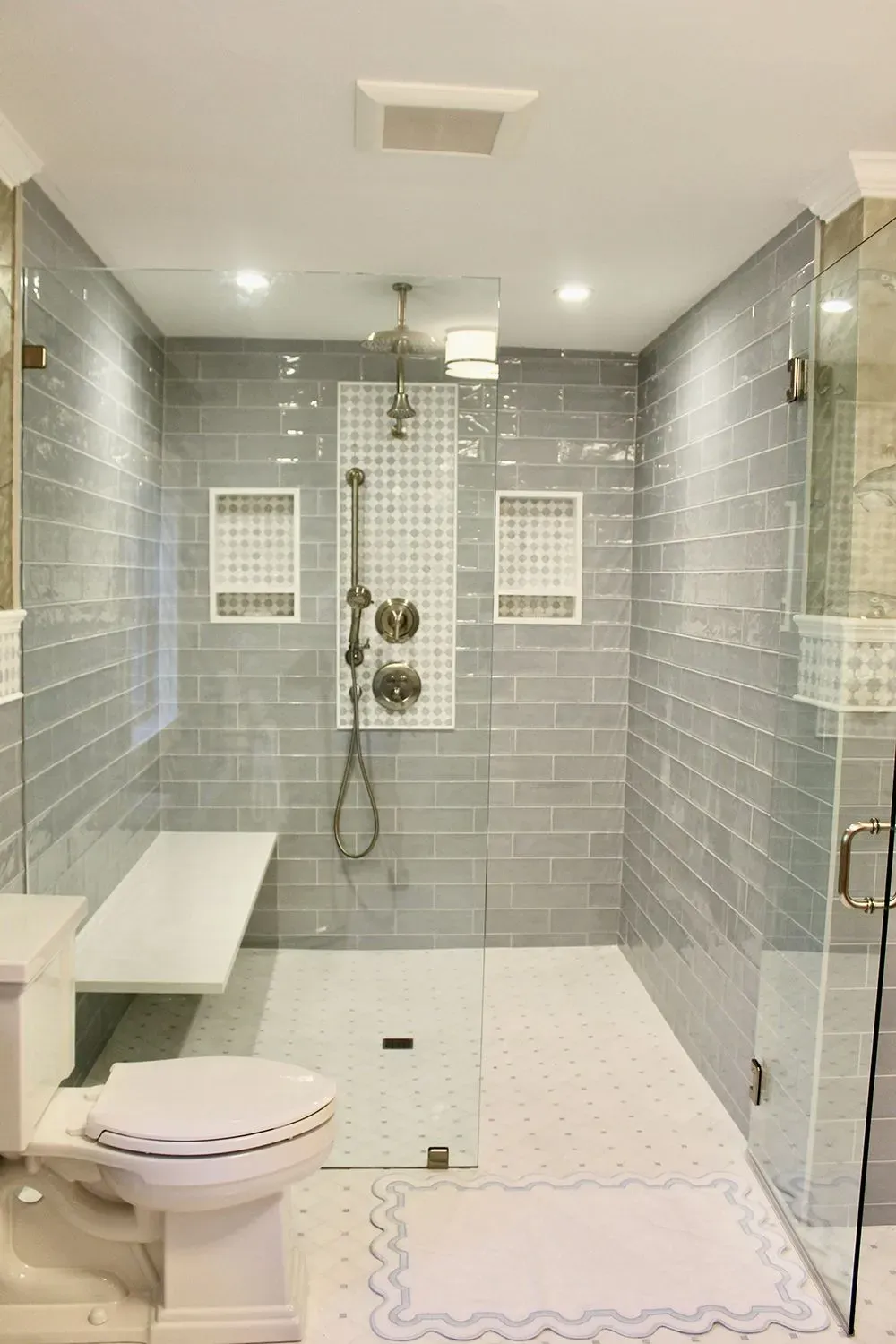 A bathroom with a toilet, shower, and bench.
