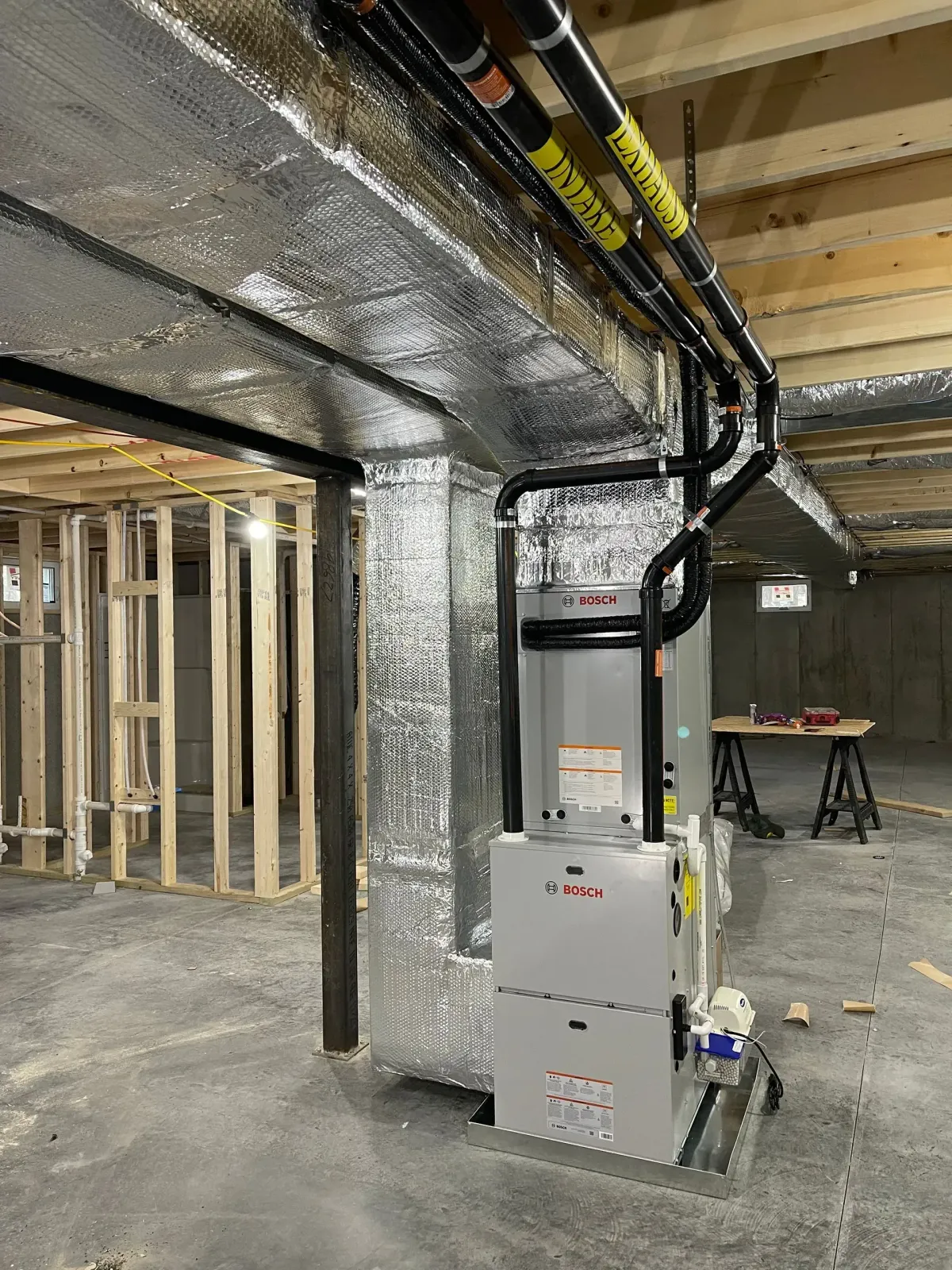 Basement utility room with HVAC furnace, exposed joists, and electrical/ductwork overhead