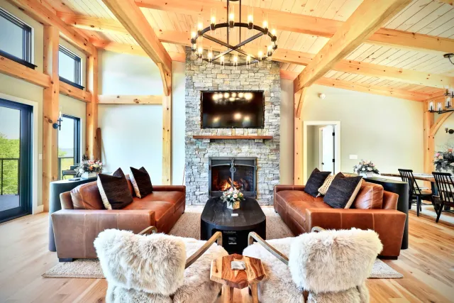 Stone fireplace and timber ceiling above leather sofas and soft white chairs in the Killington great room.