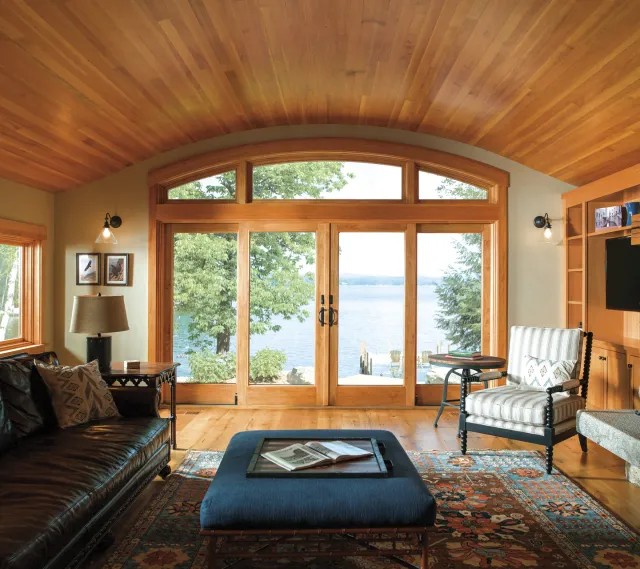 Interior view of wood sliding glass door with lakefront view and arched transom windows
