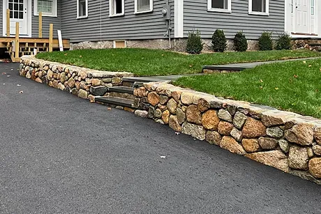 A stone wall with stairs leading up to a house.