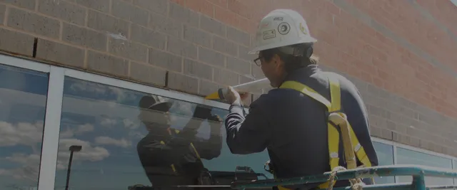man re-caulking window