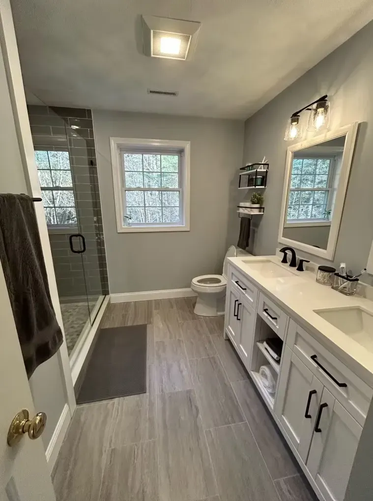 A bathroom with two sinks, a toilet, and a walk-in shower.
