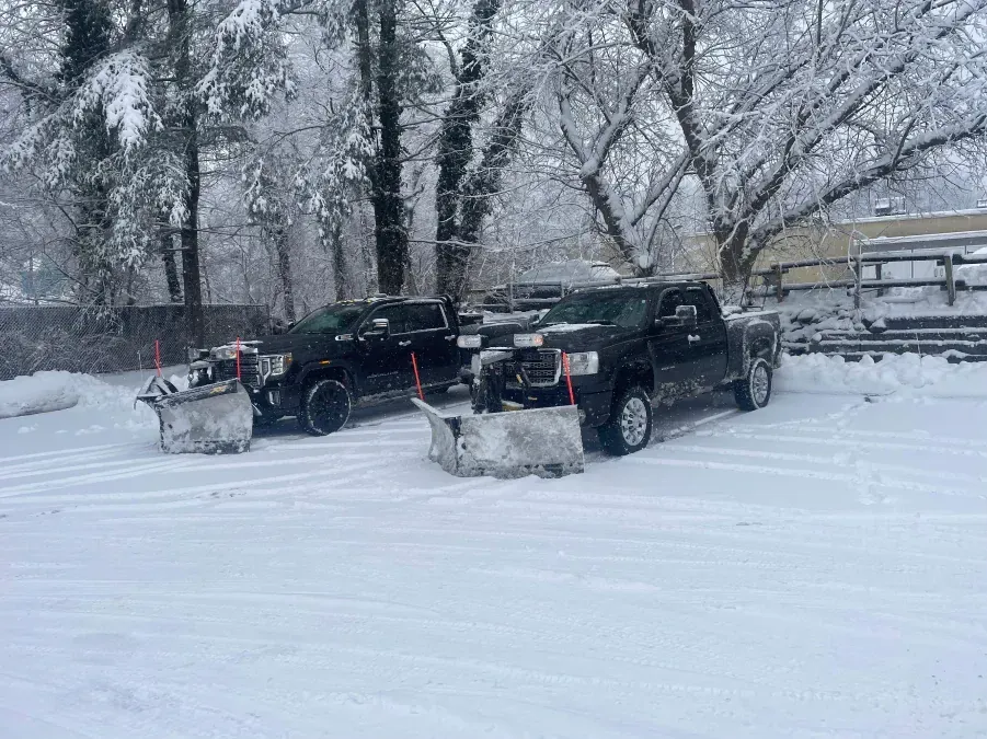 Two snow plows are parked next to each other in the snow.