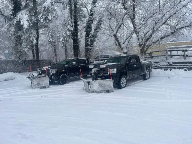 Two snow plows are parked next to each other in the snow.