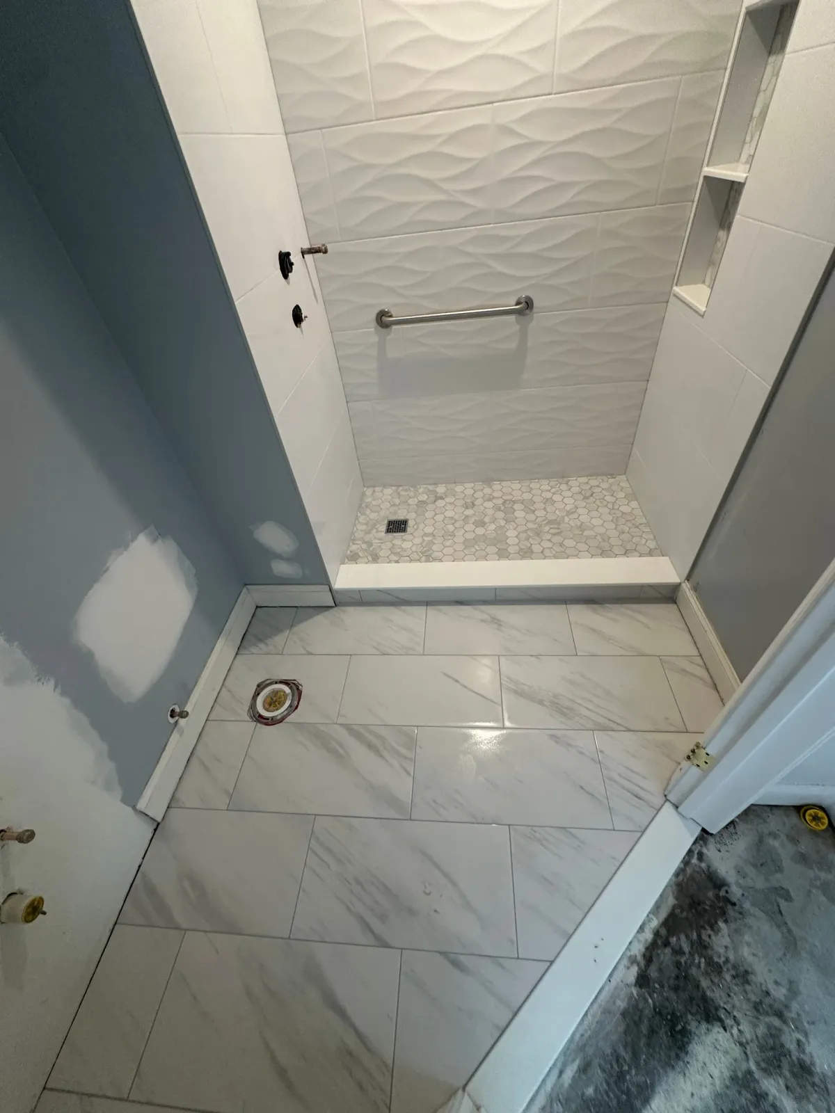 Small bathroom with white tile floor, shower stall, and gray-blue walls.
