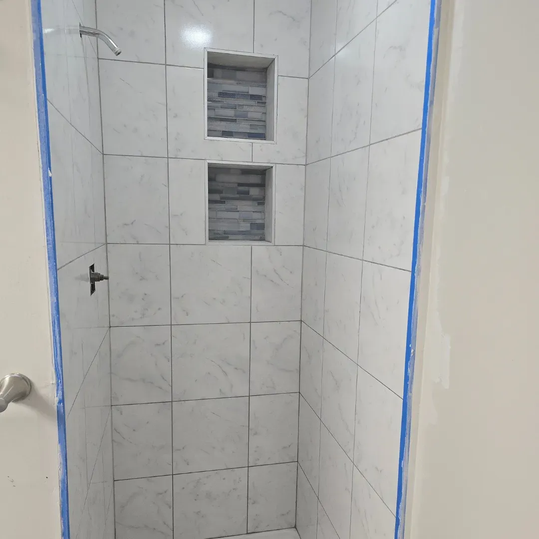 Carrara marble subway tile shower with double niche backed in glass mosaic by Link Services Pro in Shrewsbury, MA