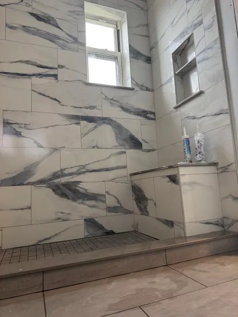 custom tile shower with a bench and a niche