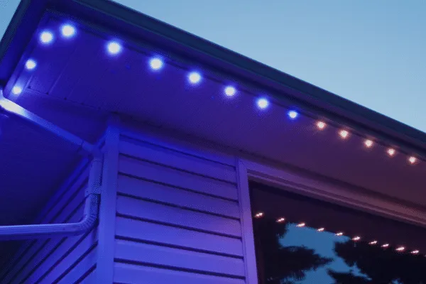 Permanent lighting on the eaves of a house shines with blue and warm white LEDs, enhancing the home's exterior at dusk.