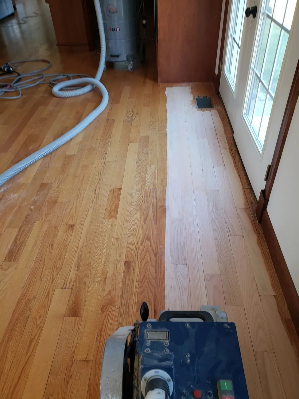 A machine is being used to sand a wooden floor