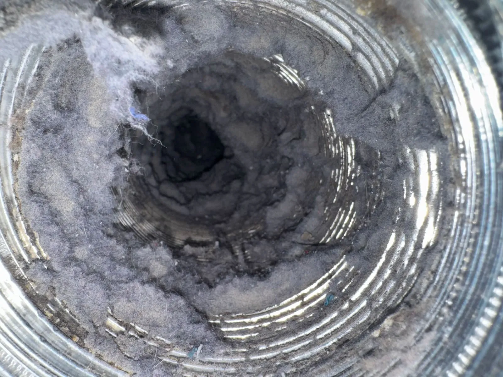 Heavy grey lint accumulation coating the full interior circumference of a dryer duct.