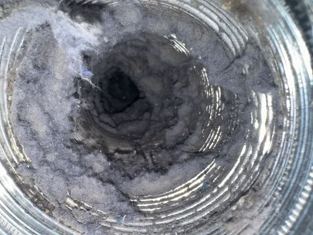 Heavy grey lint accumulation coating the full interior circumference of a dryer duct.