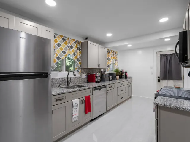 A kitchen with stainless steel appliances , granite counter tops , and gray cabinets.