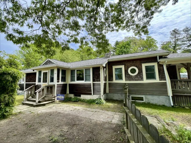 Front view of the Plymouth ranch showing the Driftwood asphalt roof, dark cedar shingle siding, cream trim, and a paver patio