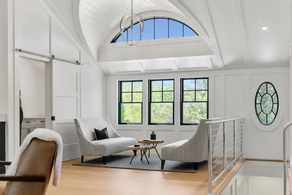 Sitting area in a modern home with wood floor, chairs, and large windows