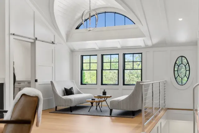 Sitting area in a modern home with wood floor, chairs, and large windows