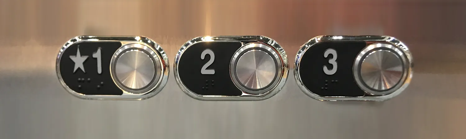 A close-up image of elevator push buttons, showcasing a clean and orderly arrangement. The buttons are well-lit and clearly labeled for each floor, set against a sleek, metallic panel.