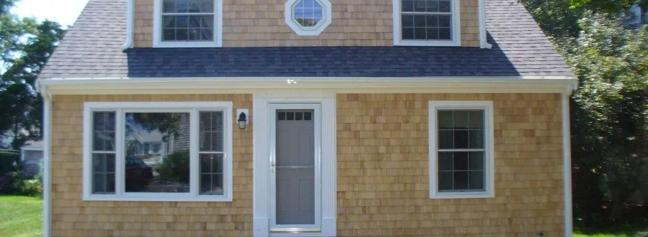 A small Cape Cod home with brand new cedar siding and white painted trim