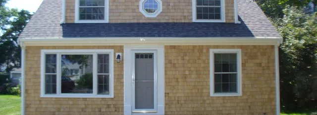A small Cape Cod home with brand new cedar siding and white painted trim