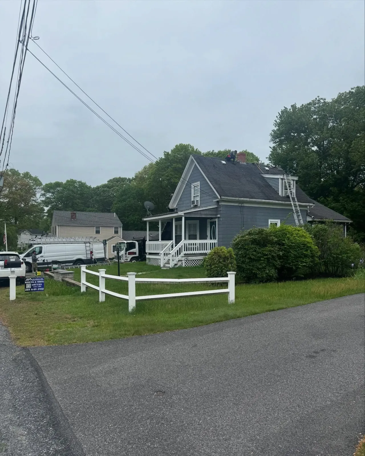 A gray house with a white fence in front of it.