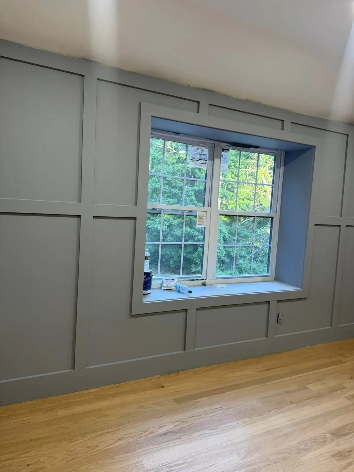 Gray board and batten wall with a framed window and fresh oak hardwood flooring by Beaver Home Remodeling