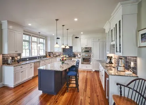 A kitchen with white cabinets , granite counter tops , and hardwood floors.