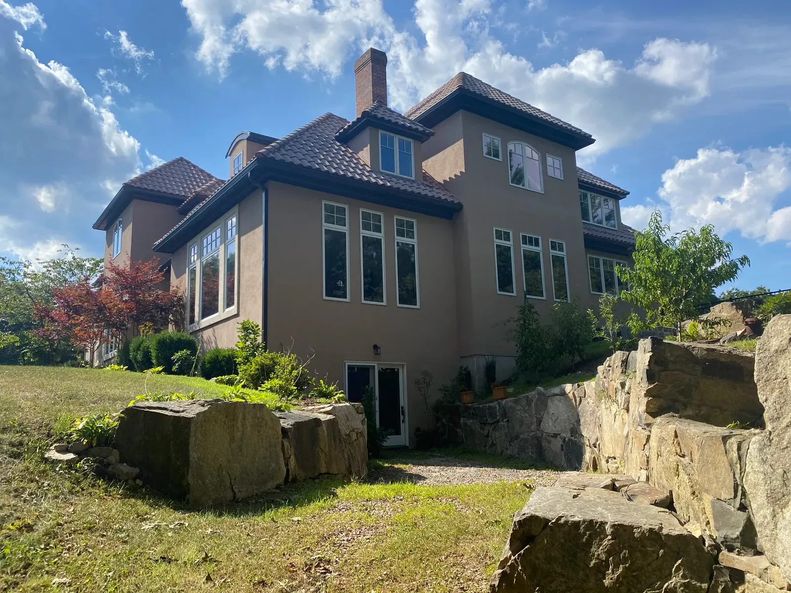 Large stucco home with dark gutter system installed around the roofline