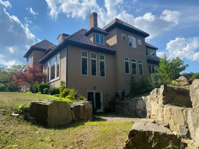 Large stucco home with dark gutter system installed around the roofline