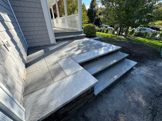 Gray stone steps leading to white porch with landscaped yard