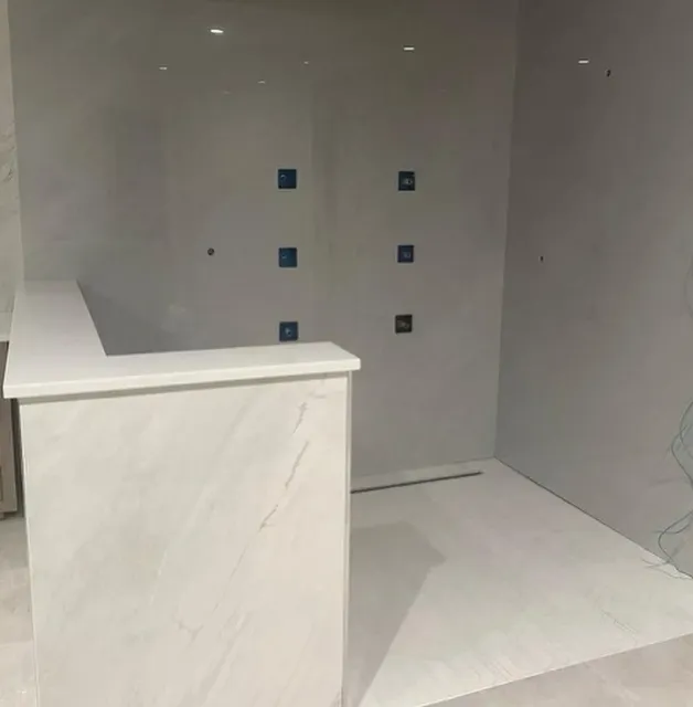 A bathroom with white tiles and blue squares on the wall.