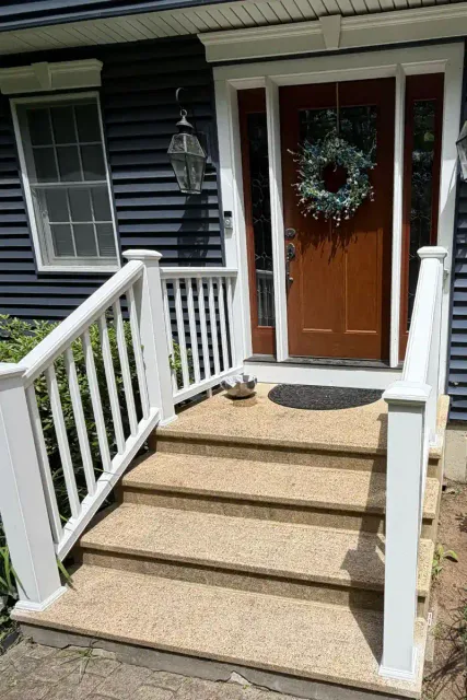 White painted porch railing and non-slip stair treads leading to a navy blue home's front entrance