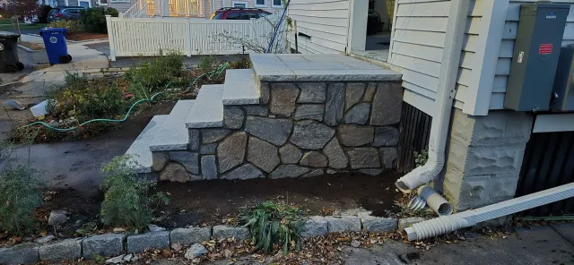 Stone steps leading to a house, with a newly landscaped area.