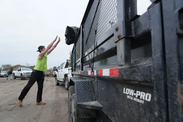 A Dump Guy trash hauler tossing a bag of trash into a large trailer
