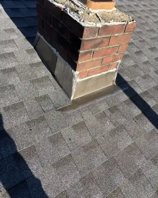 Close-up of chimney step flashing and shingle detail on a repaired roof in Bedford NH