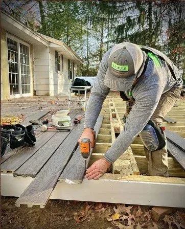 A man in a hat is focused on constructing a deck, showcasing his dedication to the project at hand.