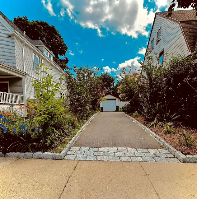A driveway leading to a white house with a garage