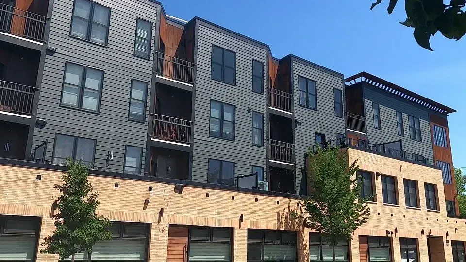 Multi-story apartment building with brick facade and gray siding.