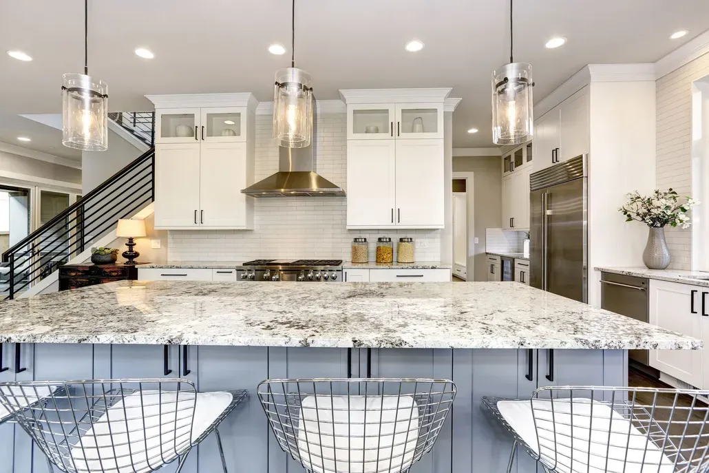 Modern white kitchen with granite island, pendant lights, and metal barstools