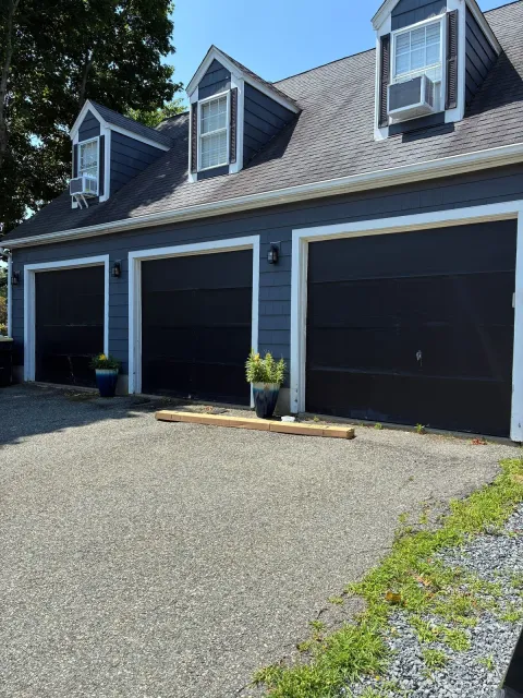 Garage doors before replacement — worn dark doors on a navy-sided home