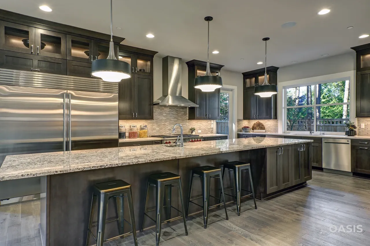 Completed kitchen with dark cabinets, long stone island, and pendant lights
