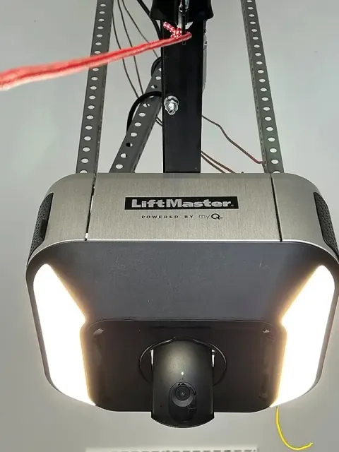 Close-up of a ceiling-mounted garage door opener with LED light panels and a built-in camera