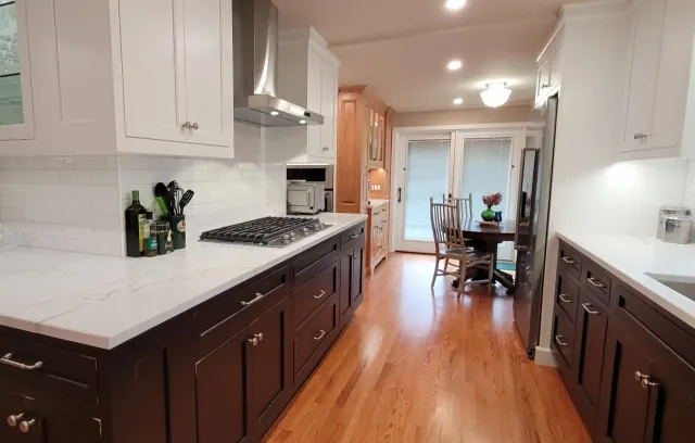 A kitchen with wooden floors and white cabinets and a stove top oven.