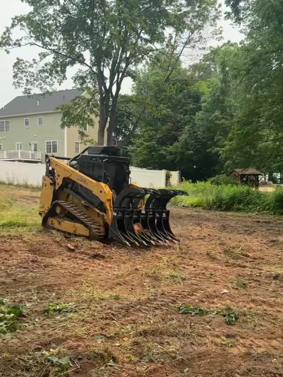 Yellow loader clearing land near trees