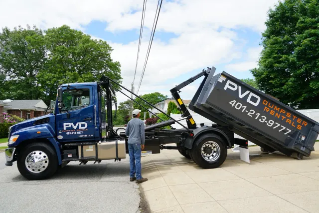 Driver unloading a 15 yard dumpster from the truck in Rhode Island