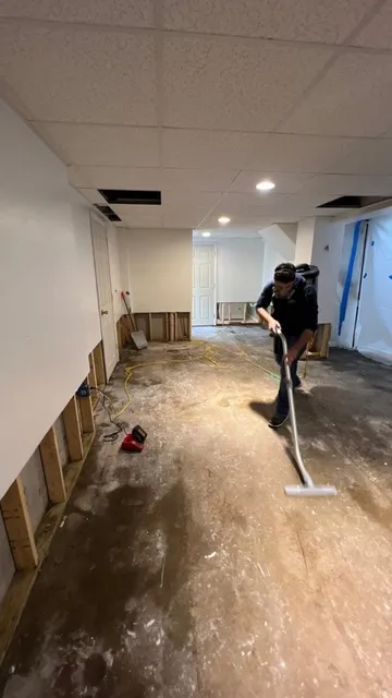 Technician cleaning a basement floor after lower wall materials were removed