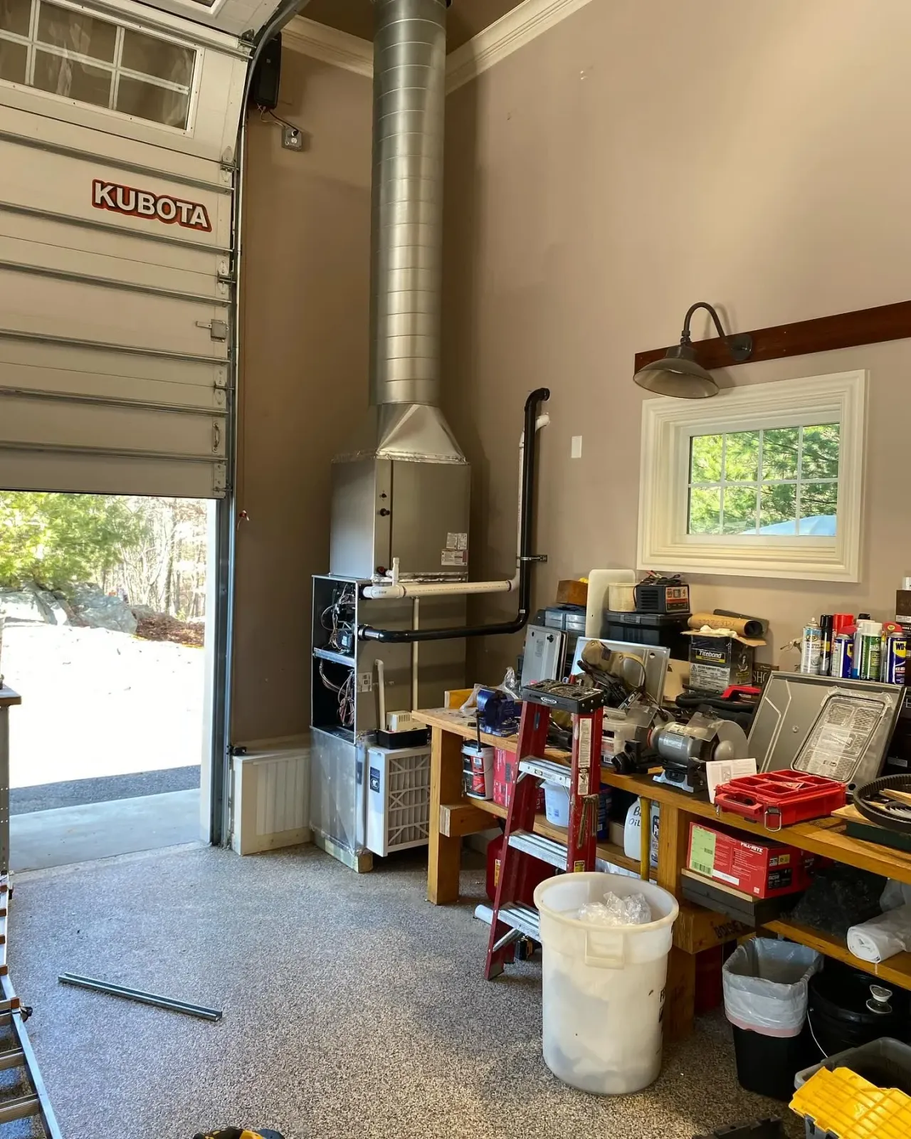 A garage with a garage door open and a lot of tools on the floor.