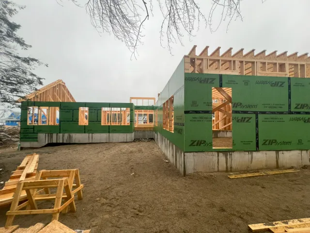 Ground-level view of green ZIP System wall sheathing installed over a poured concrete foundation.